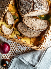 Freshly baked bread with grains cut into slices in a wooden box with maple leaves and on a cloth background.