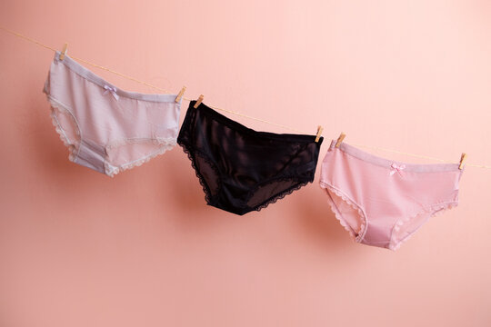 colorful clean women's panties hang on a rope. on a pink isolated background