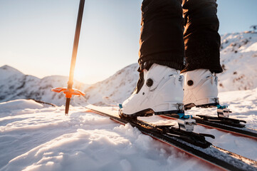 Mountaineer backcountry ski walking in the mountains. Ski touring in high alpine landscape. Adventure winter extreme sport. Detail boots. - obrazy, fototapety, plakaty