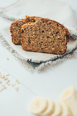 Two slice of freshly backed banana and oaten bread on gray napkin over wooden table. Healthy homemade breakfast. 