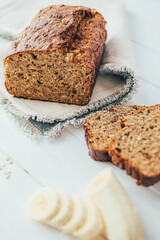 Freshly backed banana and oaten bread on gray napkin over wooden table. Healthy homemade breakfast. 