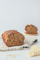 Freshly backed banana and oaten bread on gray napkin over wooden table. Healthy homemade breakfast. Copy space.