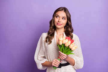 Photo portrait of woman curious dreamy looking blank space keeping flowers isolated on pastel purple color background