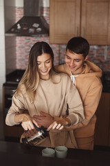 Happy couple making tea together at the kitchen - 415124548