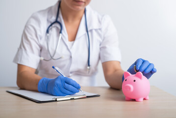 A faceless female doctor puts a coin in a piggy bank