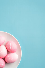 Happy Easter minimal concept. Pink Easter eggs in plate on turquoise background. Flat lay, top view, copy space.
