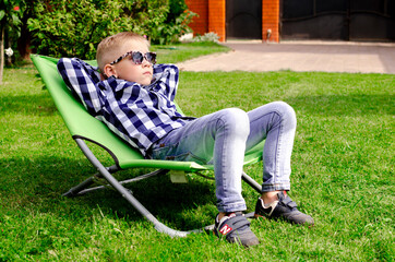 child in sunglasses on a sun lounger. family holiday. vacation in nature
