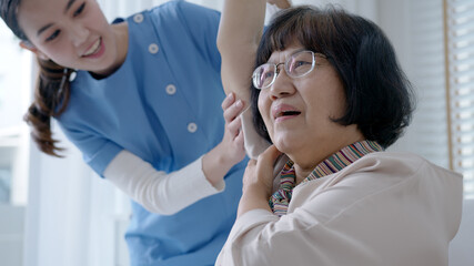 Young senior asia citizen female with scrubs nurse physiotherapy worker at home in rehabilitation...