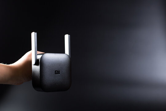 Hand holding Xiaomi wifi Amplifier Pro. Xiaomi Amplifier on black with copy space. Editorial Xiaomi Pro WiFi Amplifier.