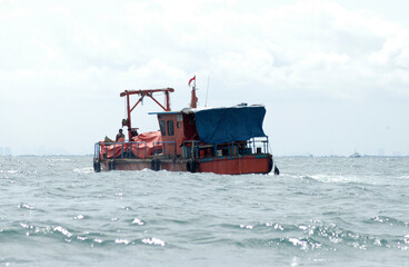 Fototapeta na wymiar A small vessel bring a cargo, crossing the sea