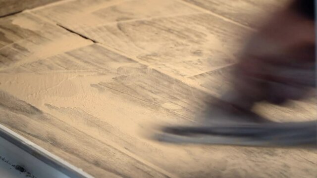 Defocused blurred motion of male hand with the rubber applies grout on a seam between tiles