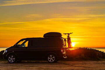 Fototapeta na wymiar Camper with bicycles on rack camping on beach at sunrise