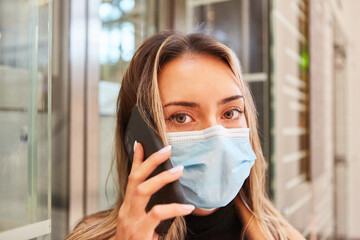 Frau mit Mund-Nasen-Schutz telefoniert mit Mobiltelefon