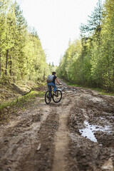 Fototapeta na wymiar The female cyclist riding on her mountain bike on the forest path. Tires on the dirty forest road. Concept of choice mtb for riding on the loam.