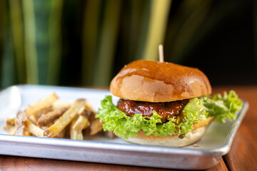 hamburguesas americanas con papas fritas en charolas de metal con mucho queso 
