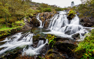 Fototapeta na wymiar Waterfall among rocks and green plants