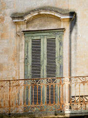 Fototapeta na wymiar Wrought iron balcony and old green shutters on the home in old town of Matera.