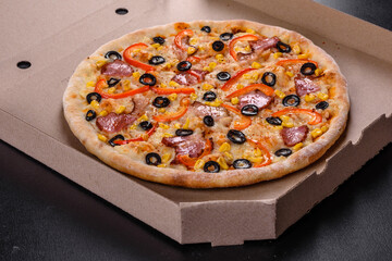 Fresh delicious pizza made in a hearth oven with olives, chili pepper and ham