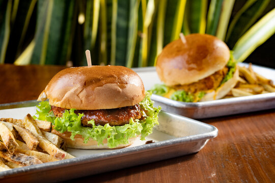 hamburguesas americanas con papas fritas en charolas de metal con mucho queso 
