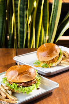 hamburguesas americanas con papas fritas en charolas de metal con mucho queso 
