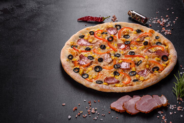 Fresh delicious pizza made in a hearth oven with olives, chili pepper and ham