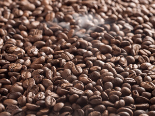 Roasted arabica coffee beans with steam emanating from them after roasting.
