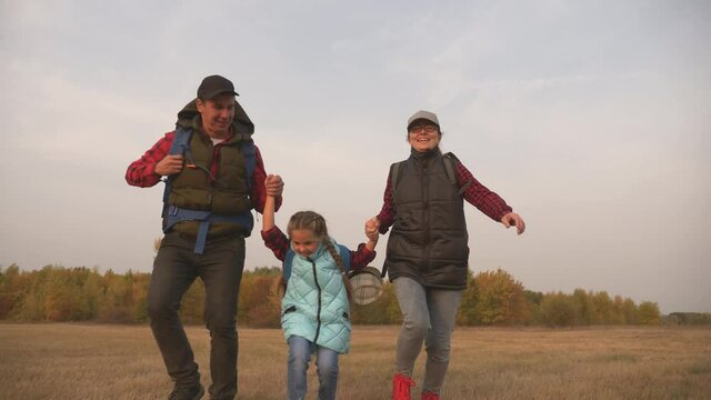 Happy family, hiking walking together outdoors. Happy child with parents walks in the park. The child holds the parents' hand. Helping hand. family team travels hiking.