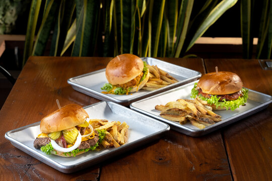 hamburguesas americanas con papas fritas en charolas de metal con mucho queso 
