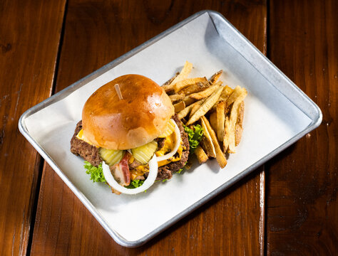 hamburguesas americanas con papas fritas en charolas de metal con mucho queso 
