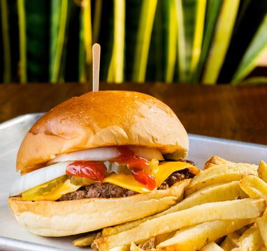 hamburguesas americanas con papas fritas en charolas de metal con mucho queso 
