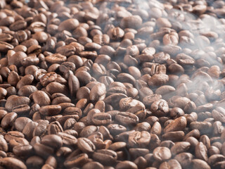 Roasted arabica coffee beans with steam emanating from them after roasting.