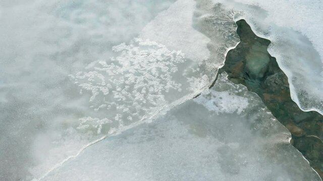 Springtime. Brittle ice, and water flow. Frozen river melting in spring. Warming, ice surface with frozen air bubbles inside