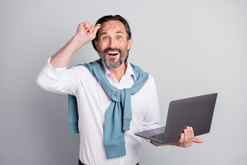 Photo portrait of surprised happy man holding laptop working on project start-up smiling isolated pastel grey color background