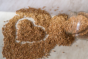 Heart shape made from buckwheat grains. Rural still-life - the peeled groats of buckwheat (Fagopyrum esculentum) on the background 