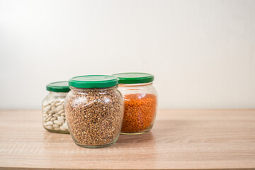 Buckwheat, Lentils, white beans in a glass jar on a wooden table