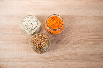 Buckwheat, Lentils, white beans in a glass jar on a wooden table
