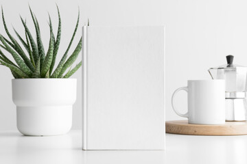 White book mockup with a succulent plant and a mug on the white table.