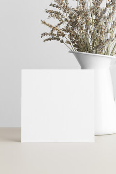 Square invitation card mockup with a dried lavender on the beige table.