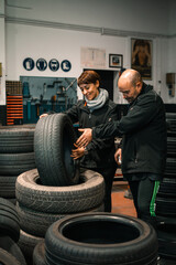 Fototapeta na wymiar Auto repair service center. Two mechanics - man and woman examining some wheels