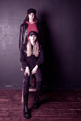 Obraz premium Two charming teenage girls with bright makeup, dressed in a grunge style, against a dark wall.