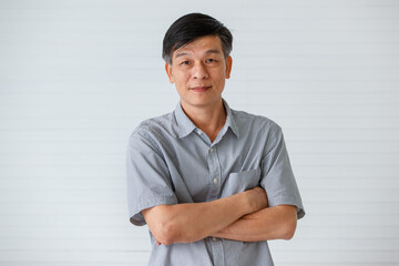 Portrait of warm personality senior older Asian man in casual dress crossed his arms over chest and friendly pose and laughing with happy and successful feeling and self-confident