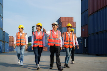 Asian foreman walking and explaining the various operations in the container depot terminal with four new trainees worker..