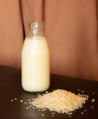 Glass bottle with vegetable rice milk and rice. Lactose-free milk, vegetarianism.