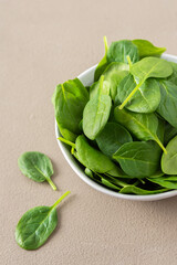 Healthy vegetable greens in a bowl on a gray background, green spinach leaves close up, top view