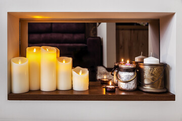 led electric and wax candles stand in the home fireplace