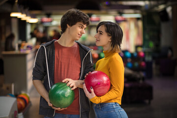Fototapeta premium Young couple having fun in bowling alley. Holding a bowler.