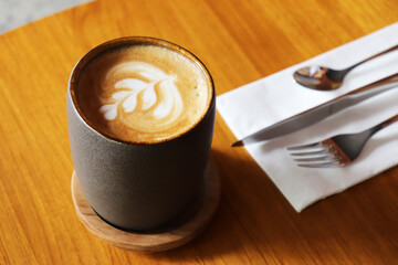 A cup of Cafe Latte, served perfectly on timber table.