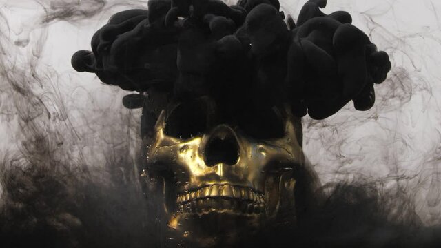 A cloud of black paint covers a golden skull