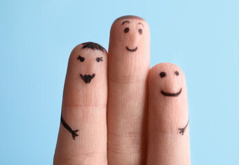 Three fingers with drawings of happy faces on light blue background