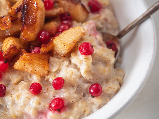 Oatmeal in milk with fruit additives, caramelized apples and red currants